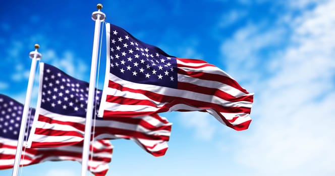 Three flags of the United States of America waving in the wind. Clear sky in the background. Selective focus. Democracy, independence and election day. Patriotic symbol of American pride