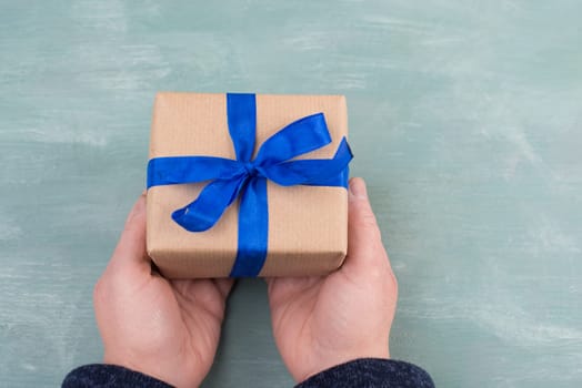 Holding a gift box in the hands, blue colored background