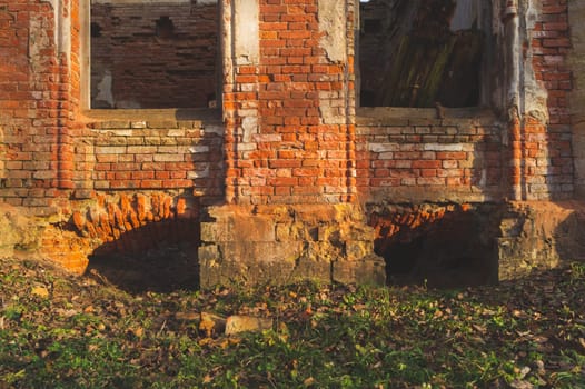 Destroyed wall. overgrown windows in brick wall of old ruined building