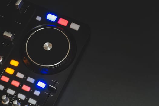 Dj sound mixer controller with knobs and sliders close up. audio mixing deck with turntables at dark with illuminated controls