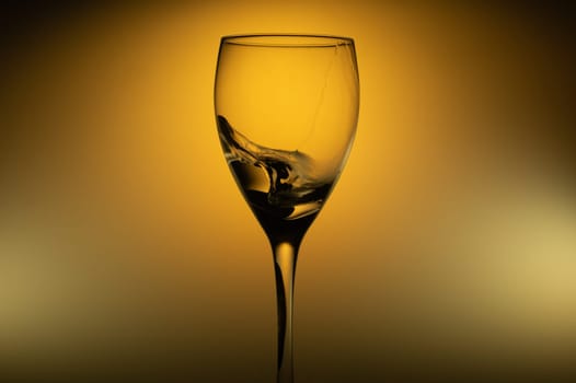 Water splash in glass on glowing background. splashing water in wine glass. transparent cocktail