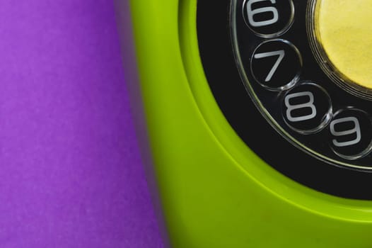Vintage rotary phone. classic green telephone with round dial isolated on purple background. old communication technology. copy space