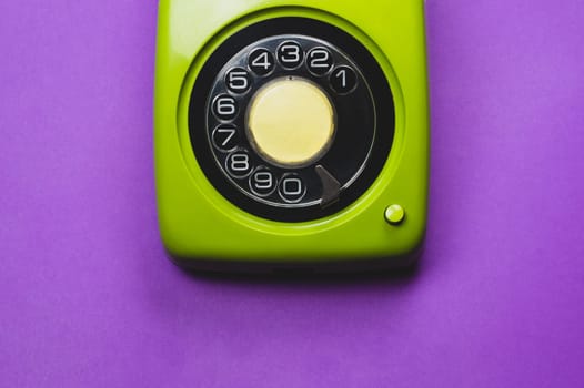 Vintage rotary phone. classic green telephone with round dial. isolated on purple background. old communication technology. copy space