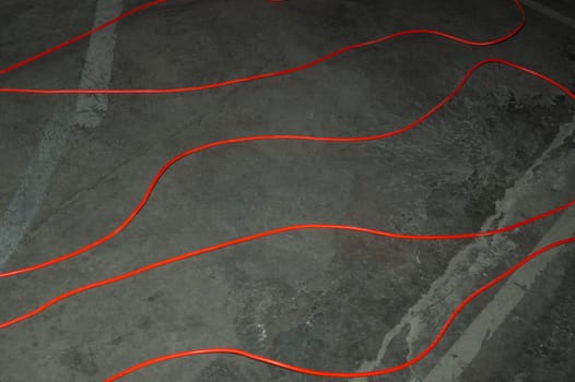 Red electric power cable. red wire lies on the ground. mess on cement floor. industrial background