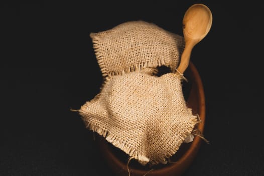 Honey pots with linen cloth with wooden spoon on dark background