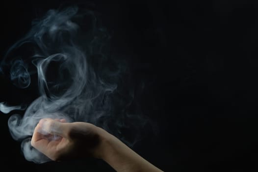 Smoke in hand. abstract fog in the dark. hand creates a magic spell
