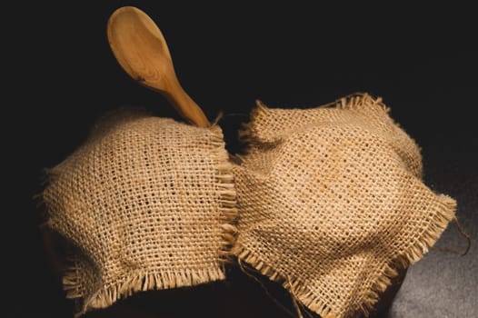 Honey pots with linen cloth with wooden spoon on dark background