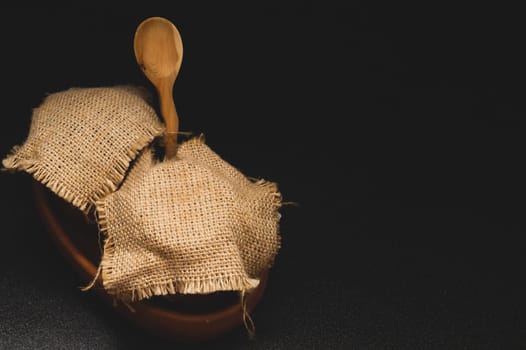Honey pots with linen cloth with wooden spoon on dark background