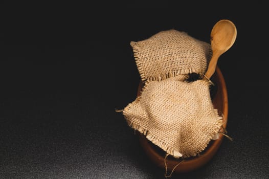 Honey pots with linen cloth with wooden spoon on dark background