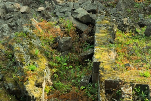 Rock of layered stone overgrown with grass and moss. texture of stone rocks. stone background