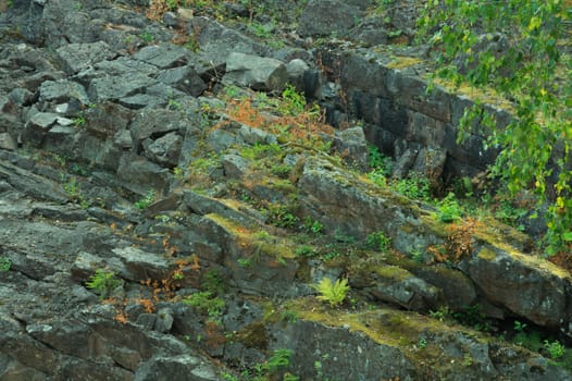 Rock of layered stone overgrown with grass and moss. texture of stone rocks. stone background