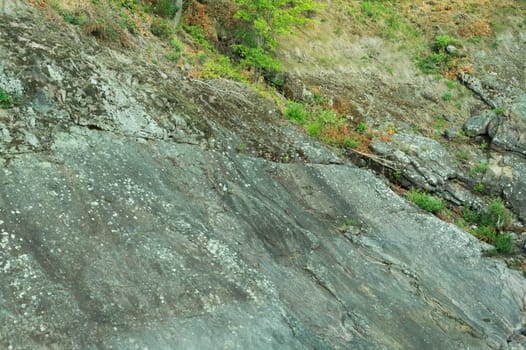 Rock of layered stone overgrown with grass and moss. texture of stone rocks. stone background