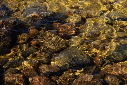 Shiny transparent water. clear water with pebbles and stone on the bottom. shining reflections of sun rays and ripples on the water surface