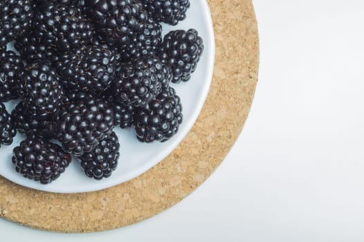 Blackberries on a plate isolated on white background. fresh berries with copy space