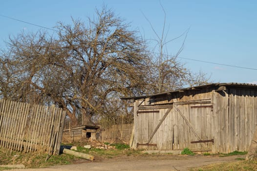 Courtyard of abandoned wooden house with small doghouse in the countryside