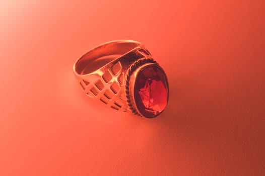 Golden ring with ruby under red light background