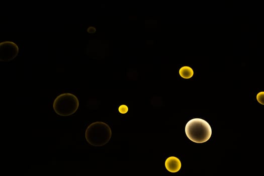White and yellow circles of different sizes glow on a black background. High quality photo