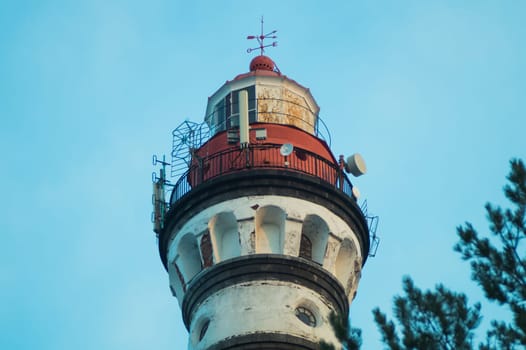 Lighthouse in the forest between the trees. red and white lighthouse background