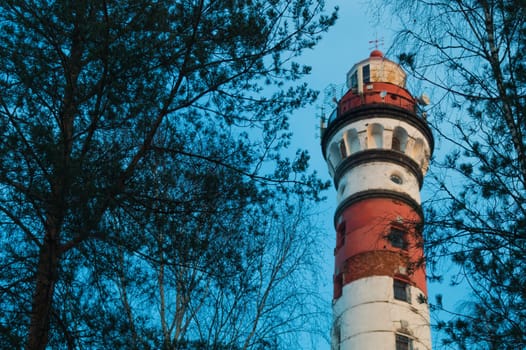 Lighthouse in the forest between the trees. red and white lighthouse background
