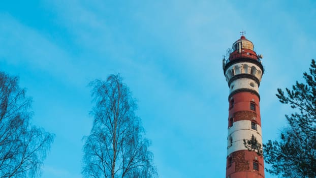 Lighthouse in the forest between the trees. red and white lighthouse background