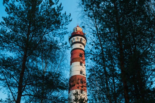 Lighthouse in the forest between the trees. red and white lighthouse background
