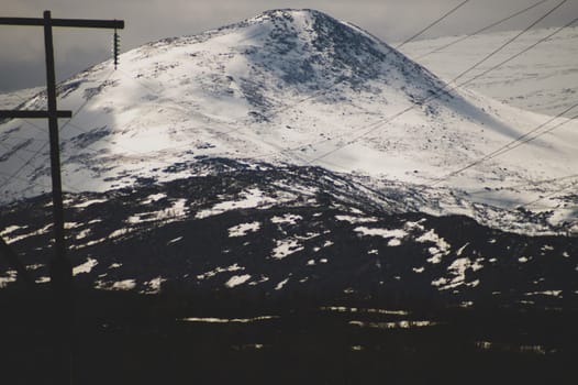Mountain landscape background. snowy hills and forest. industrial power lines in mountains