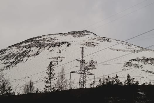Mountain landscape background. snowy hills and forest. industrial power lines in mountains