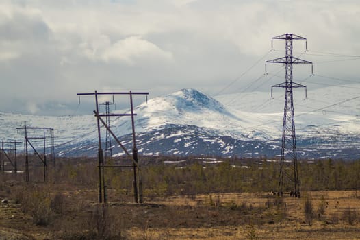 Mountain landscape background. snowy hills and forest. industrial power lines in mountains
