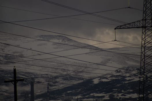 Mountain landscape background. snowy hills and forest. industrial power lines in mountains