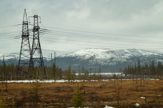 Mountain landscape background. snowy hills and forest. industrial power lines in mountains