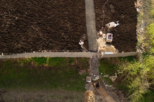 Worker manually makes a way to future parking lot. builder is busy with construction work. aerial view. manual labor concept