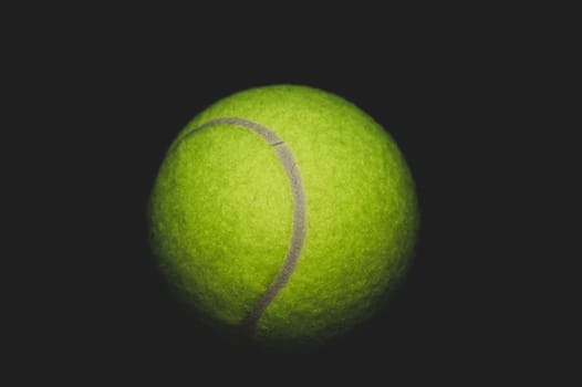 green tennis ball isolated on black background. sport equipment