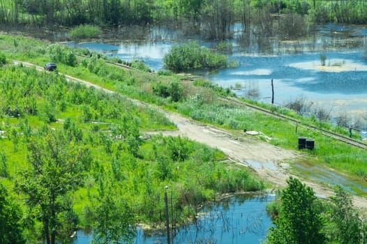 Car on the road between the swamps. railway among marshland. beautiful landscape in sunny day with aerial view. green plants and blue water