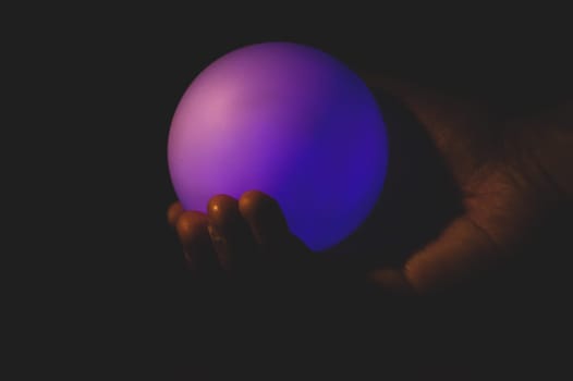 Hand holds a luminous sphere in the dark