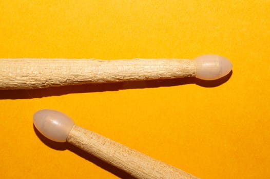 Pair of drumsticks on yellow background close up. copy space