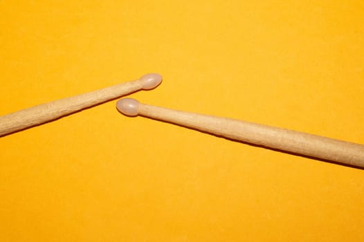 Pair of drumsticks on yellow background close up. copy space