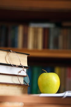 glasses on the books and green apple