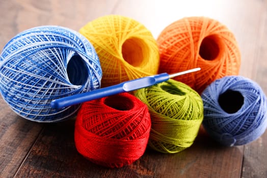 Colorful yarn for crocheting and hook on wooden table