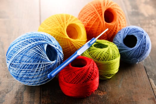 Colorful yarn for crocheting and hook on wooden table