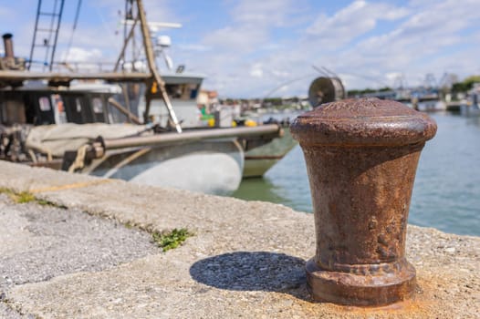 Bollard in the harbor, with the background of fishing boats