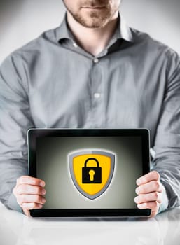 Online security concept with a businessman holding a tablet displayed to the viewer showing a yellow shield and padlock