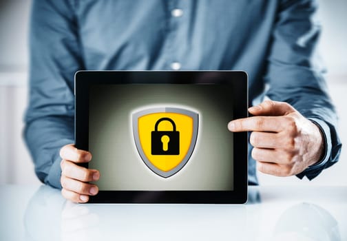 Online security concept with a man holding a tablet computer pointing to the screen displaying a yellow shield and padlock icon