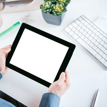 Businessman holding a tablet with a white blank screen in his hands with copyspace for your advertising or text, high angle view of his hands over his desk