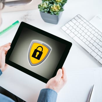 Close up Man Hands Holding a Tablet Computer with Conceptual Padlock Icon on the Screen While Sitting at his Worktable.