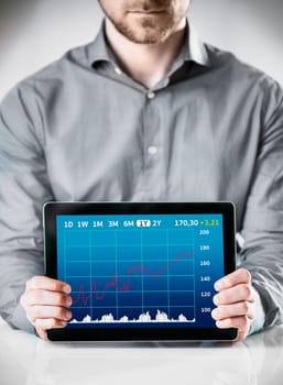 Close up Businessman Holding a Table Gadget with a Conceptual Statistical Graph Display on the Screen.