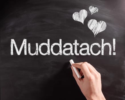 Human Hand Writing a Conceptual Muddatach Text on Black Chalkboard with Heart Shapes.
