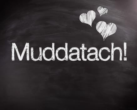 Conceptual Muddatach Word on Black Chalkboard with Heart Shape Designs, Captured in Close up.
