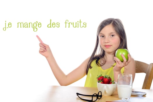a little girl sitting with an apple and strawberries on white