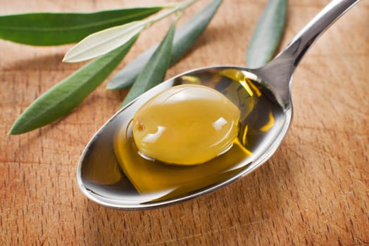 Olive fruit in spoon with oil background close up