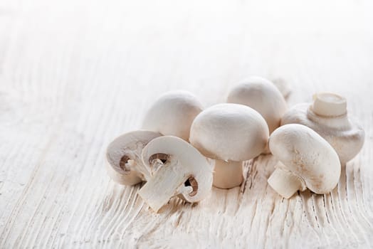 Fresh mushrooms champignons on wooden background close up